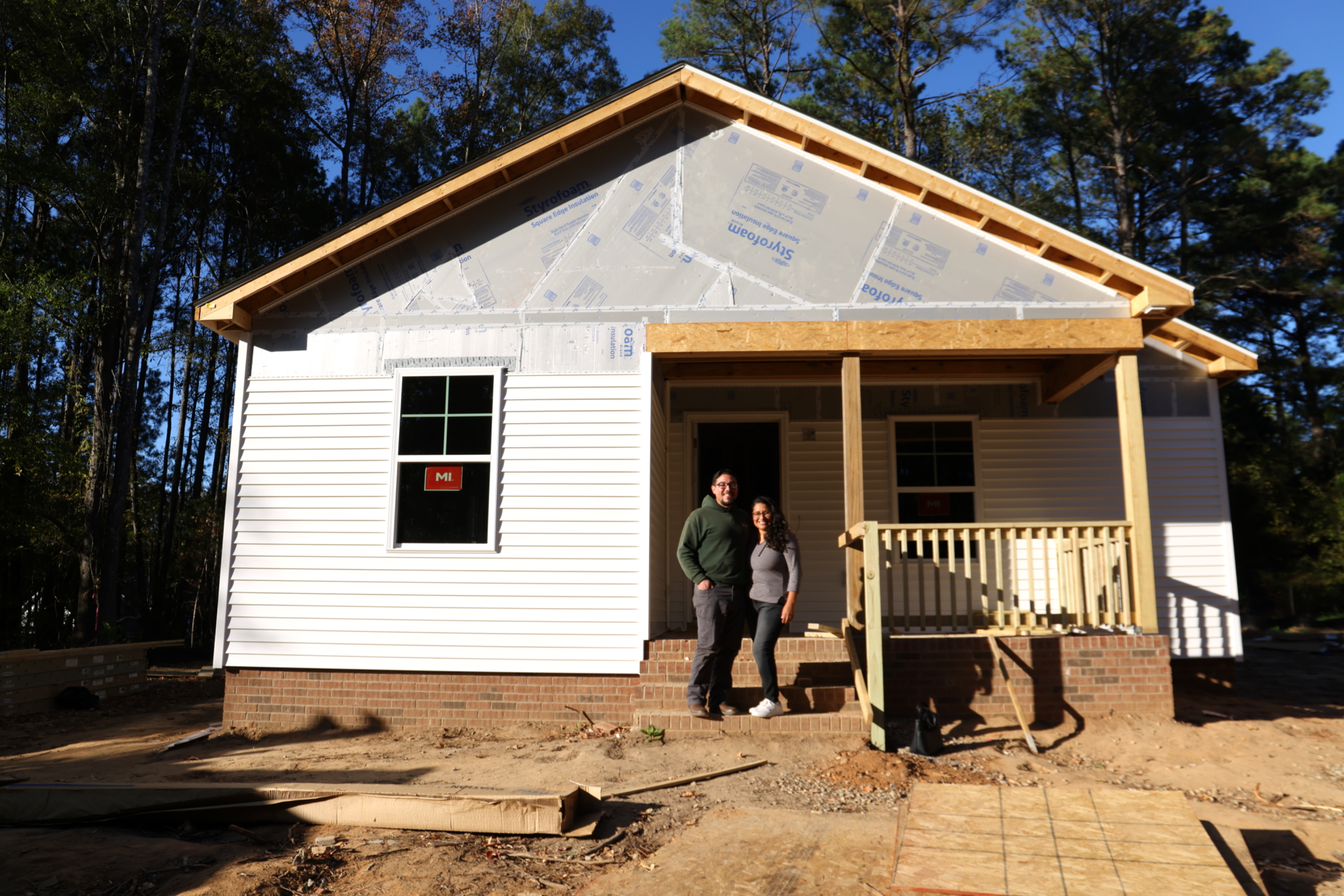 Couple stands in front of their future home