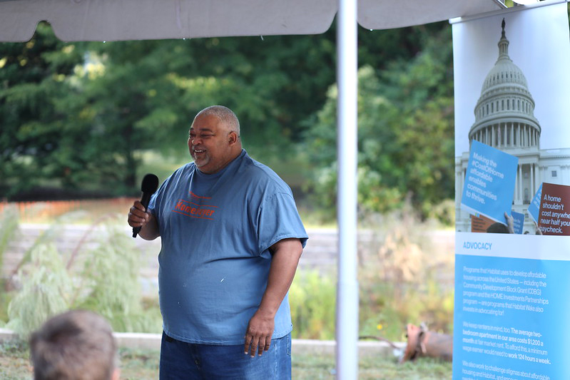 A man holds a microphone wearing a homebuyer t-shirt