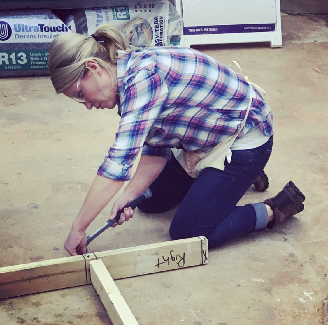 Habitat Wake Women Build board chair in the warehouse hammering on a wall frame