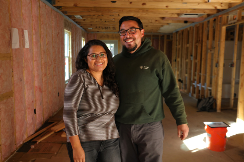 A couple stands in the framed construction of their future home