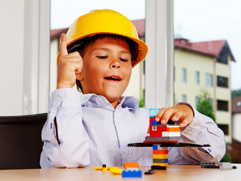 Child wearing hard hat building with Legos