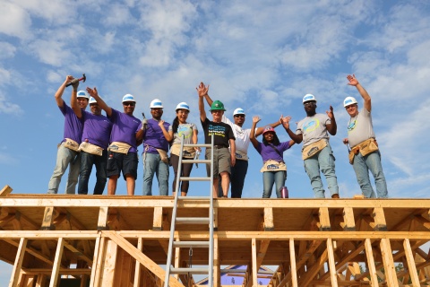 A group of volunteers standing on the roof of an in progress house