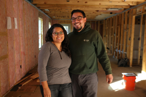A couple stands in the framed construction of their future home
