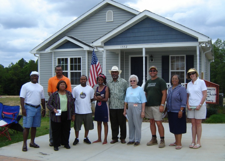 Volunteers and homeowner standing in front of a Habitat home. 